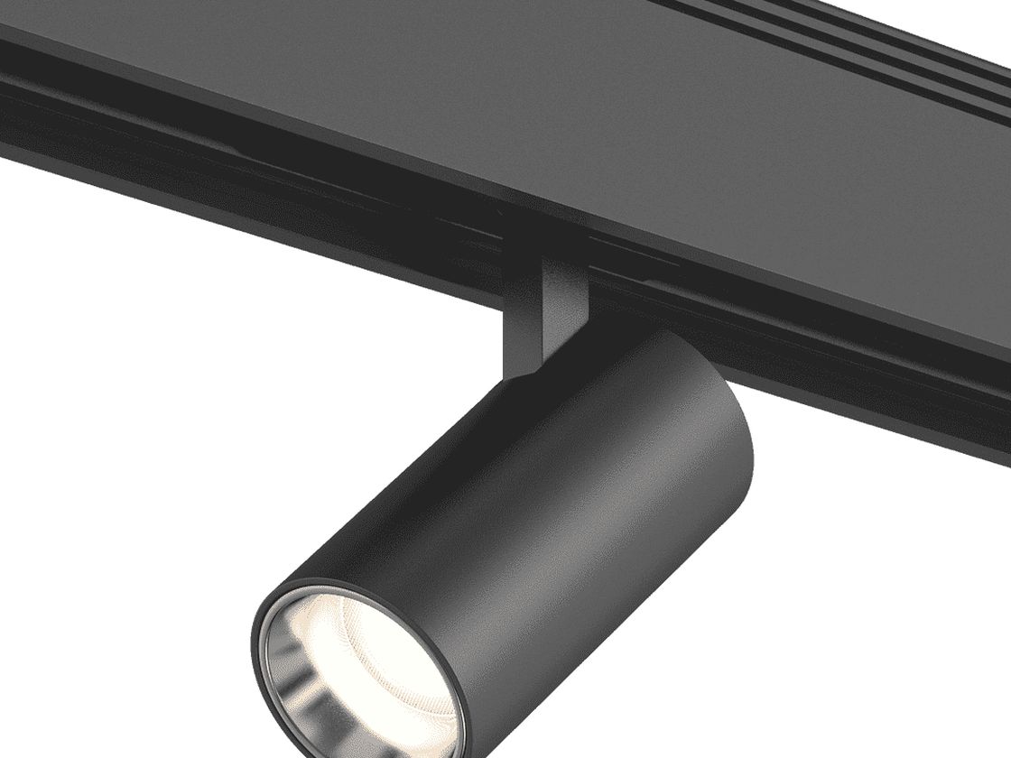Трековый светильник черный на шинопроводе, включенный теплый свет